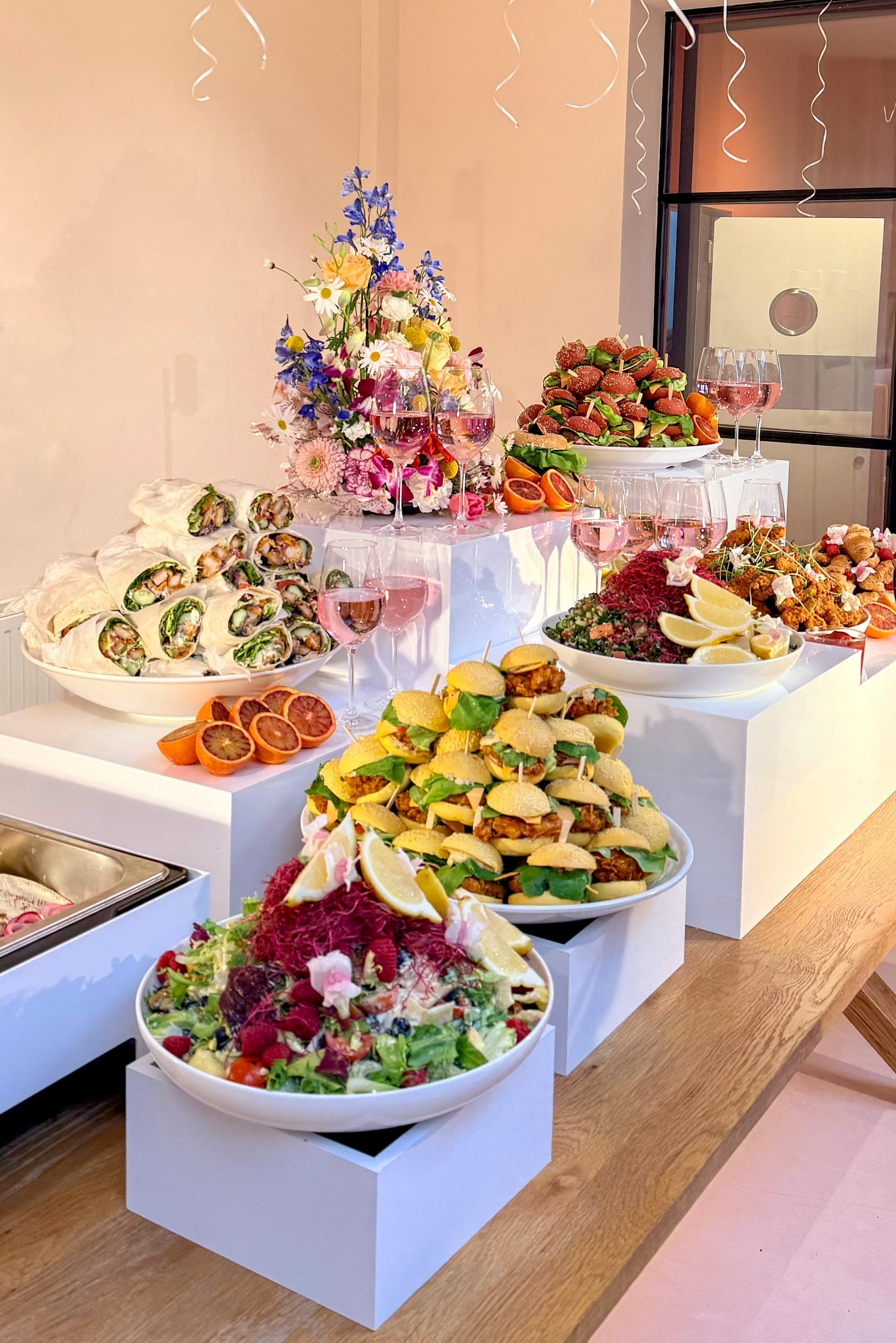 Buffet auf weißen Podesten mit Wildblumenstrauß, Kräutersalat mit roten Sprossen und frittierten Häppchen