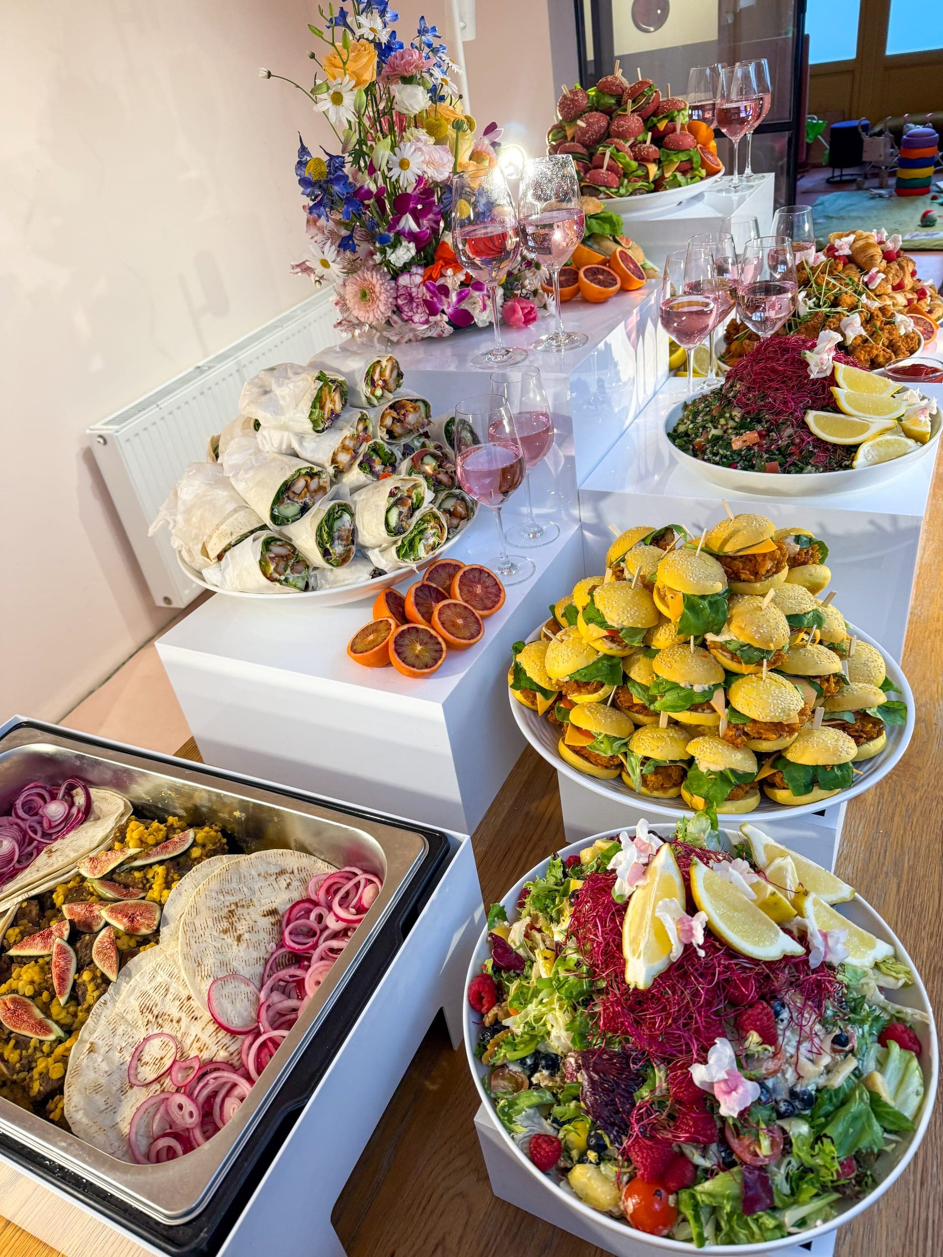 Buffet mit Fladenbrot und eingelegten Zwiebeln im Chafing Dish, Mini-Burgern auf gelben Buns und Wrap-Röllchen