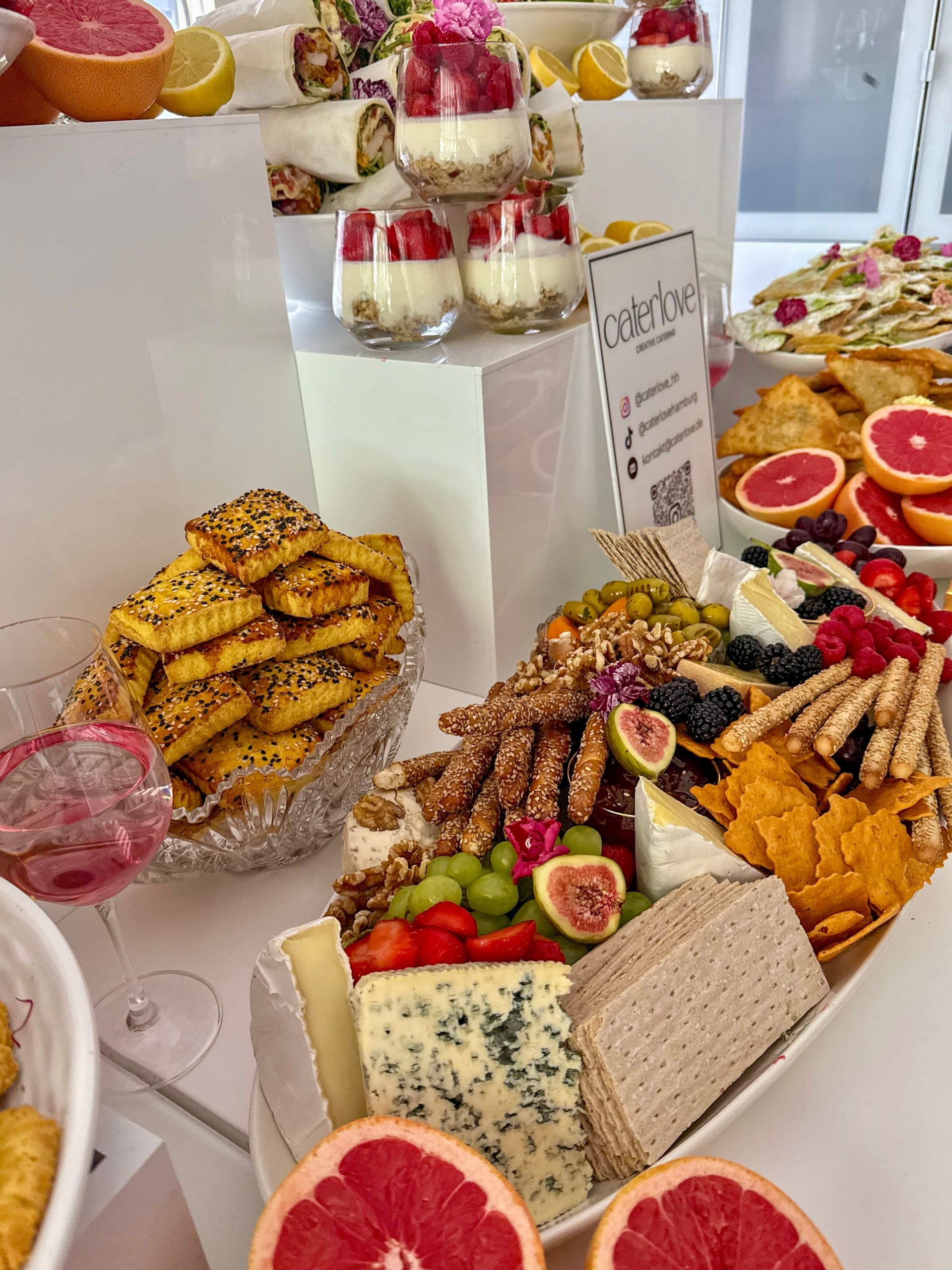 Große Platte mit Brie, Blauschimmelkäse, Grissini, Trauben, Feigen, Beeren und Oliven, daneben Sesamgebäck